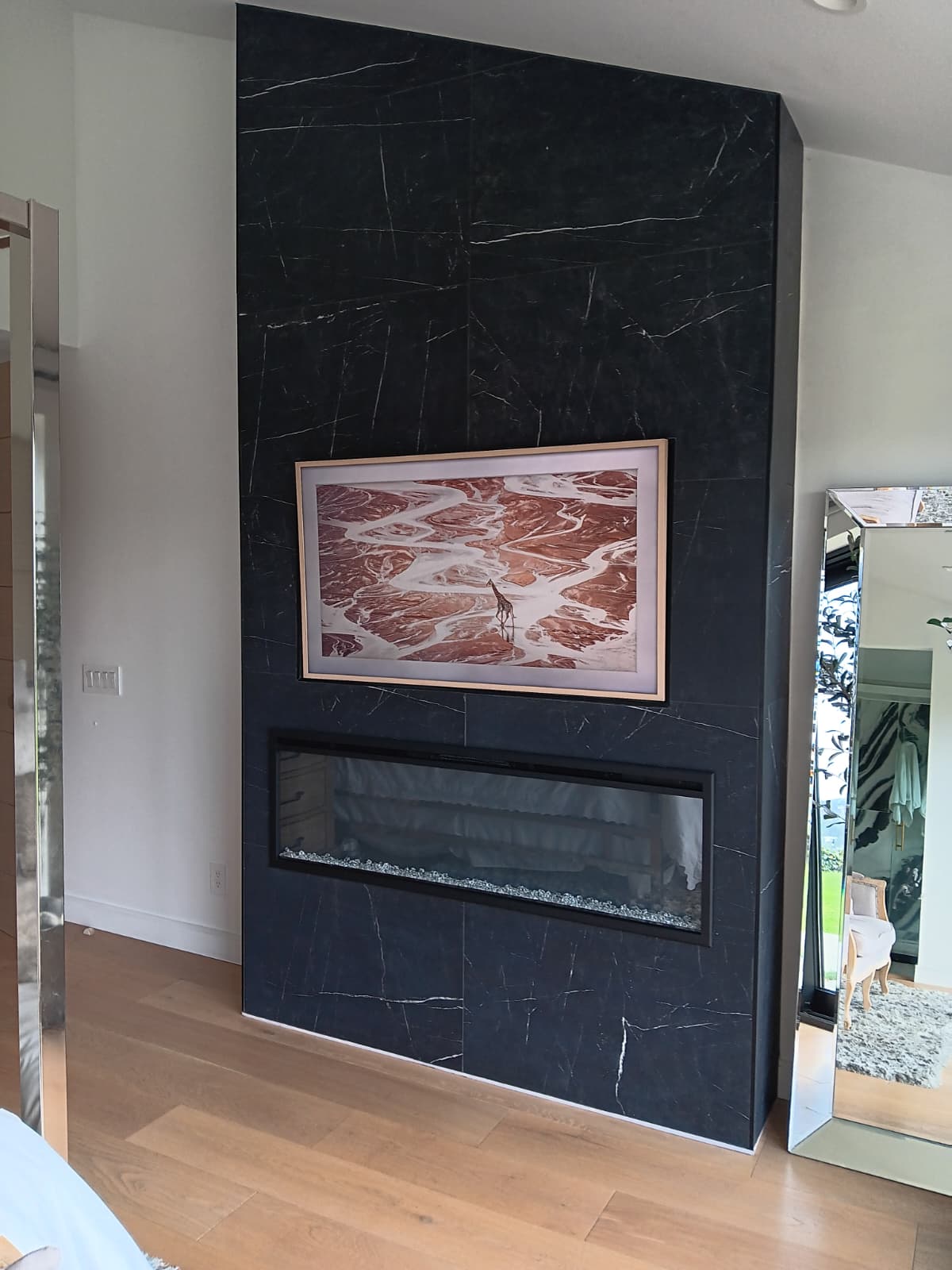 Floor-to-ceiling fireplace wall in black marble-look porcelain with a linear gas insert