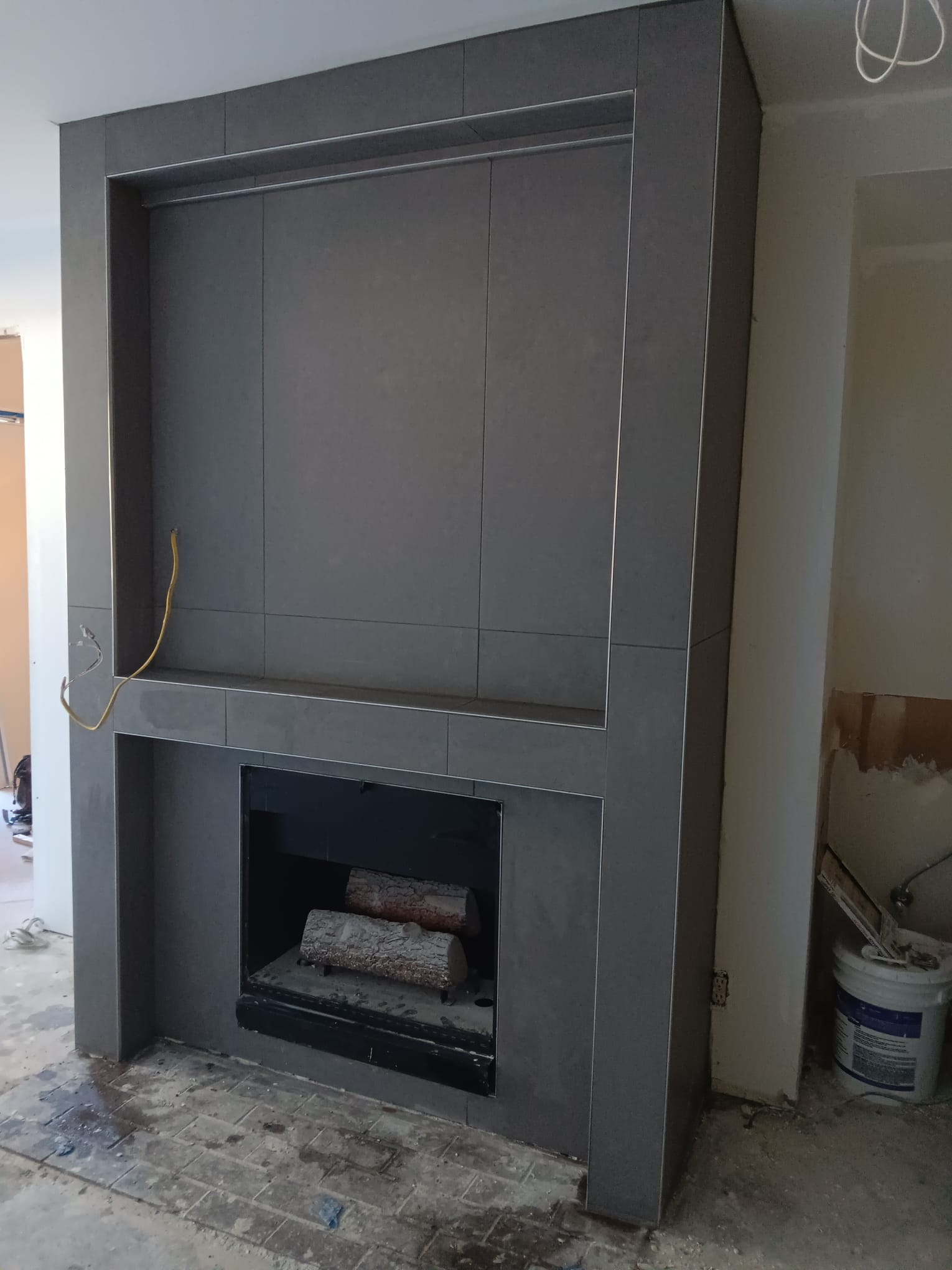 Fireplace surround and TV niche in large-format charcoal porcelain, during installation